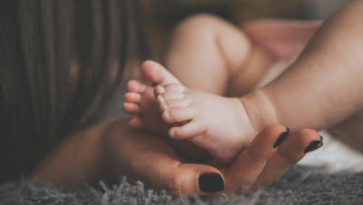A baby resting its feet in its mother’s hands.